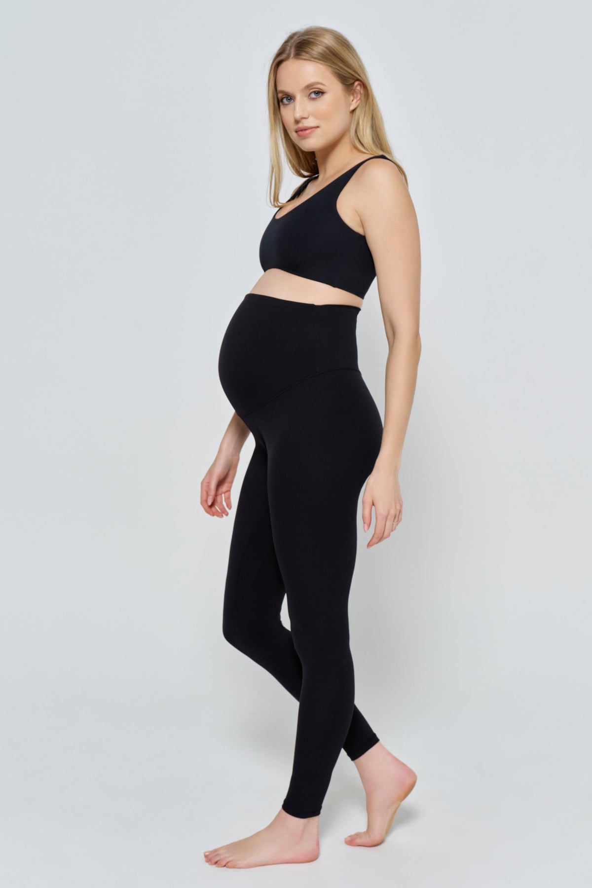 Three-quarter view of The Perfect Movement Maternity Legging showing black over-bump fit on a pregnant model against a light background