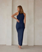 pregnant woman wearing a turtleneck dress in navy against a beige feature wall