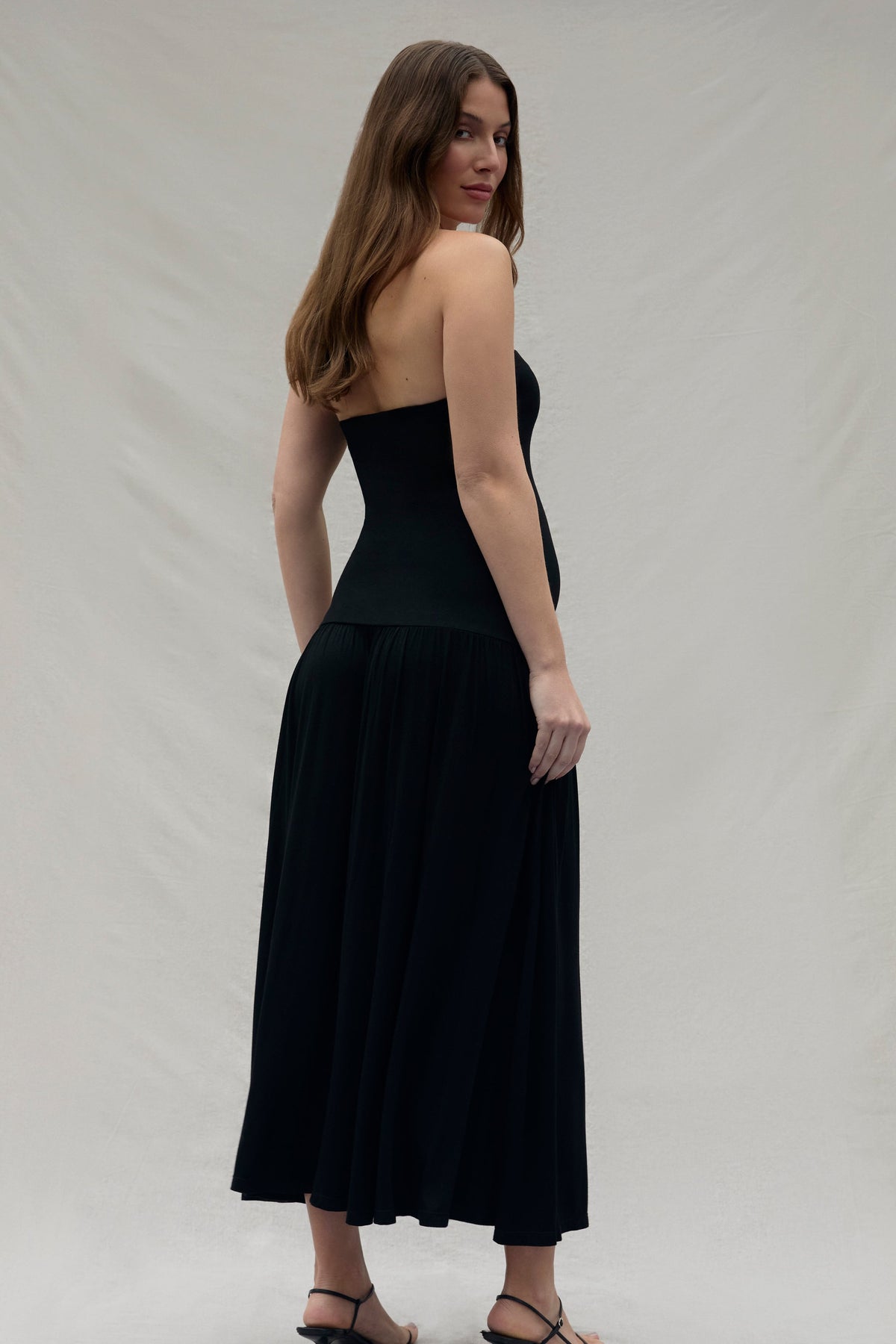 Woman wearing a black strapless dress against a plain background