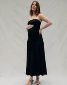 Woman wearing a black strapless dress against a plain background