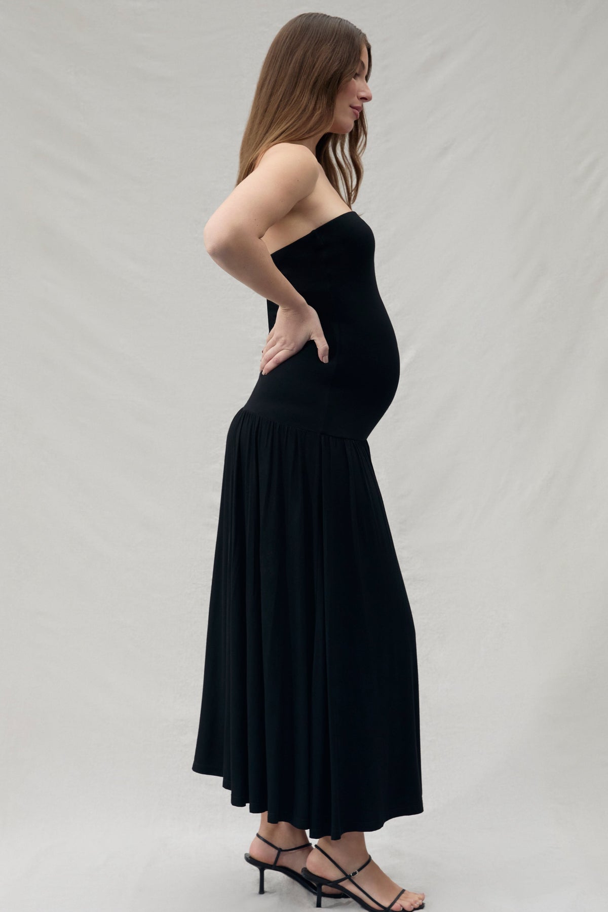 Woman wearing a black strapless dress against a plain background