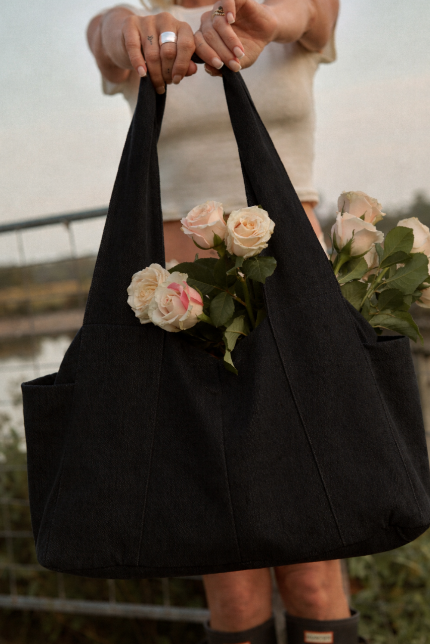 lady holding a black denim diaper bag  with roses inside