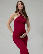 Woman wearing a burgundy dress with floral accents against a plain background