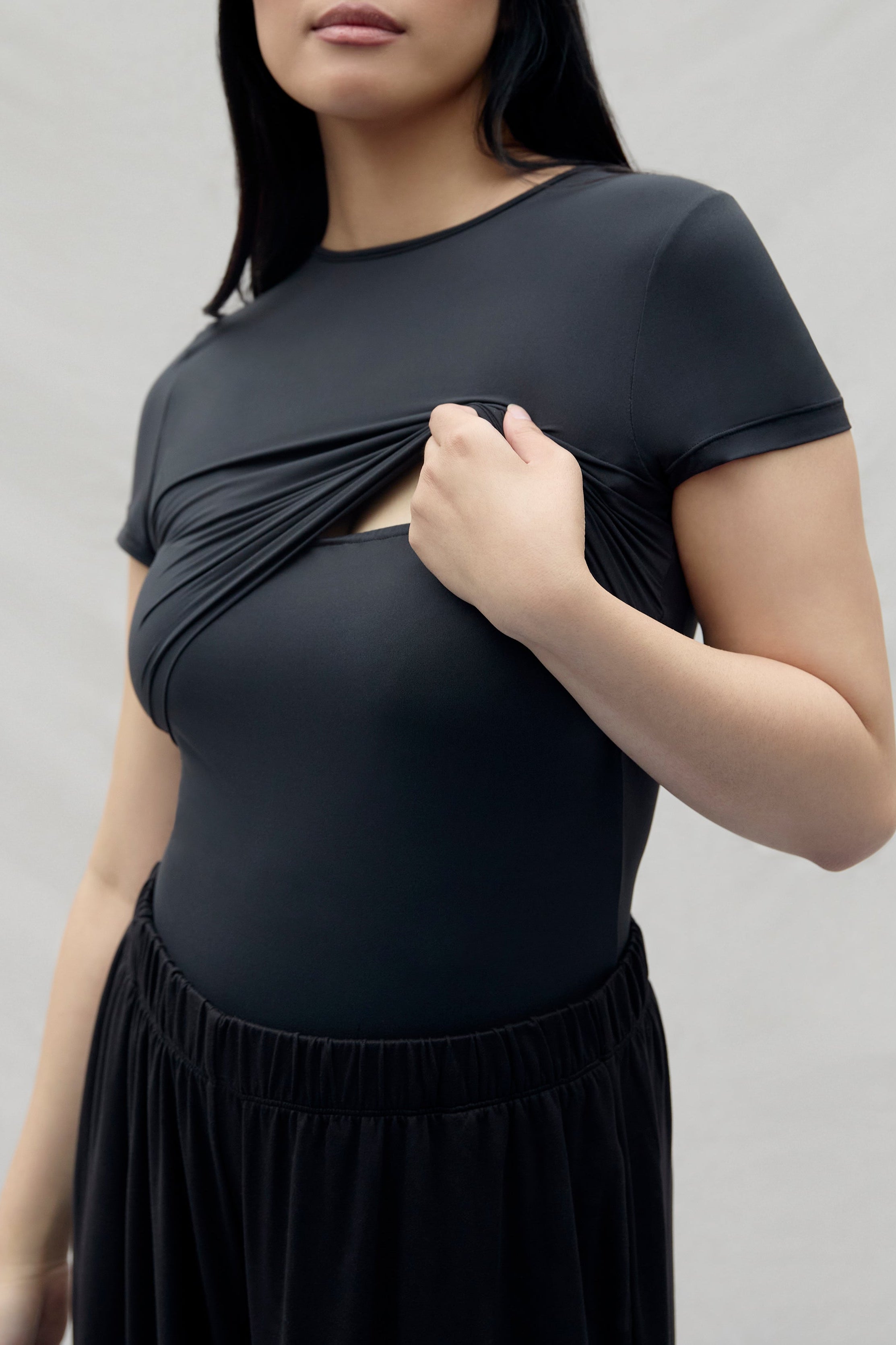 Woman pulling up a layer of a black top with breast feeding access