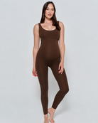 Woman wearing a chocolate brown Bumpsuit bodysuit on a light gray background