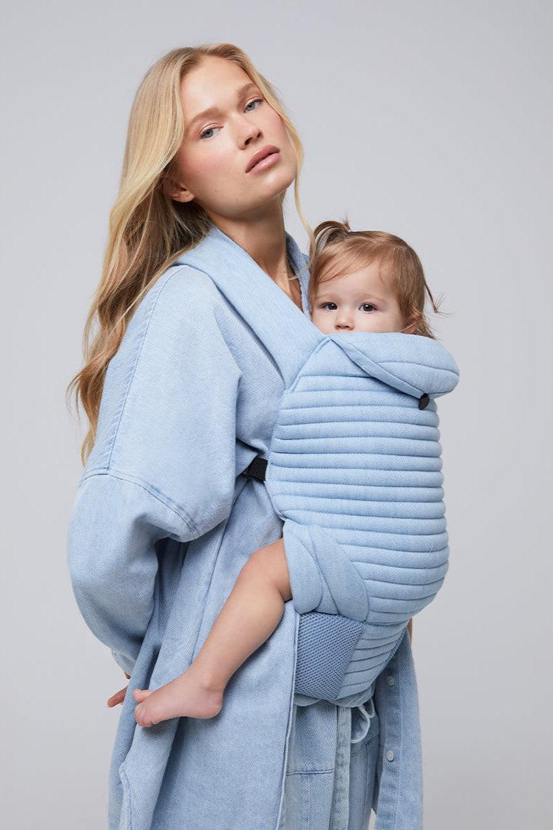 model in all denim with a baby in the light blue denim baby carrier 