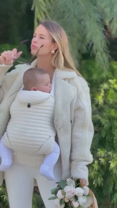 video of a lady walking in nature wearing the bumpsuit armadillo baby carrier in the cloud color 