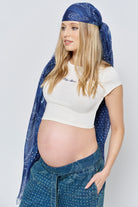 Pregnant woman wearing a blue headscarf and denim pants on a white background