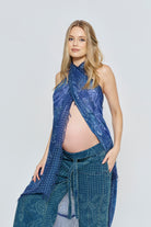 Pregnant woman wearing a blue patterned scarf and jeans outfit from Bumpsuit on a white background