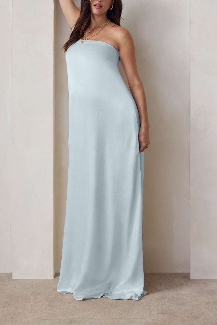 A pregnant woman wearing the Bumpsuit brushed satin strapless maxi maternity gown in powder blue against a beige feature wall
