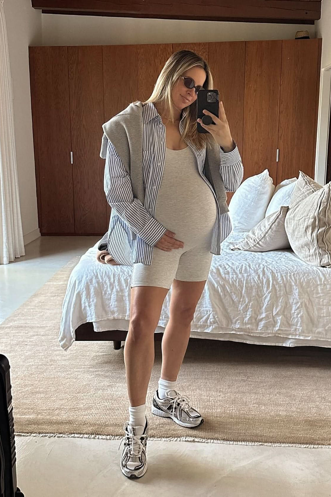 Pregnant women wearing the cindy maternity romper in heather grey in a bedroom setting