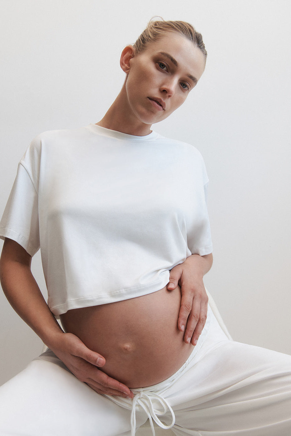 Pregnant woman wearing the cloud maternity crop tee in ivory