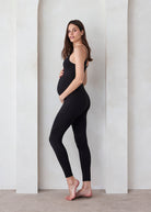A pregnant woman wearing the Kate Bumpsui against a beige background