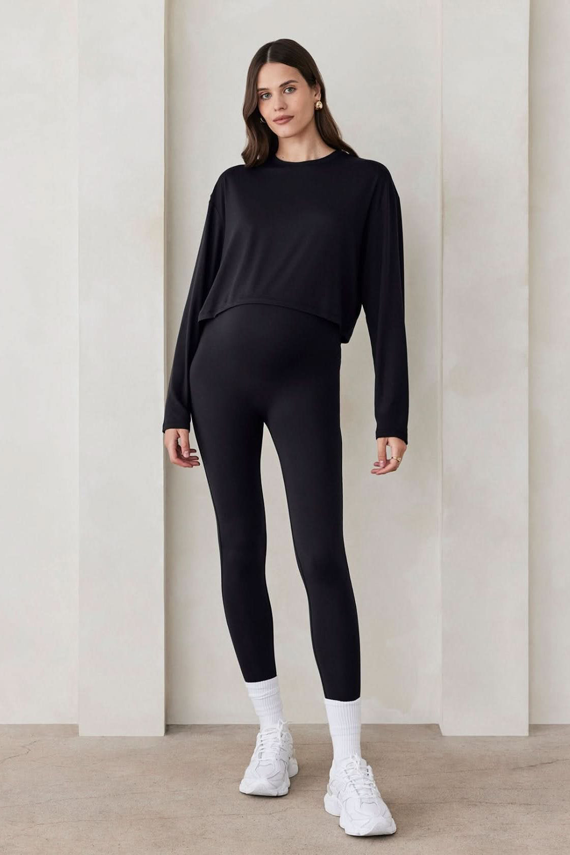 Front view of black BUMPSUIT The Maternity Legging showing the super-high-rise over-the-bump fit on a pregnant model