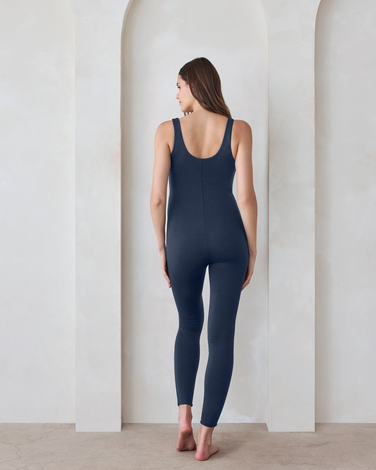 Back view of a pregnant woman in a navy jumpsuit by Bumpsuit