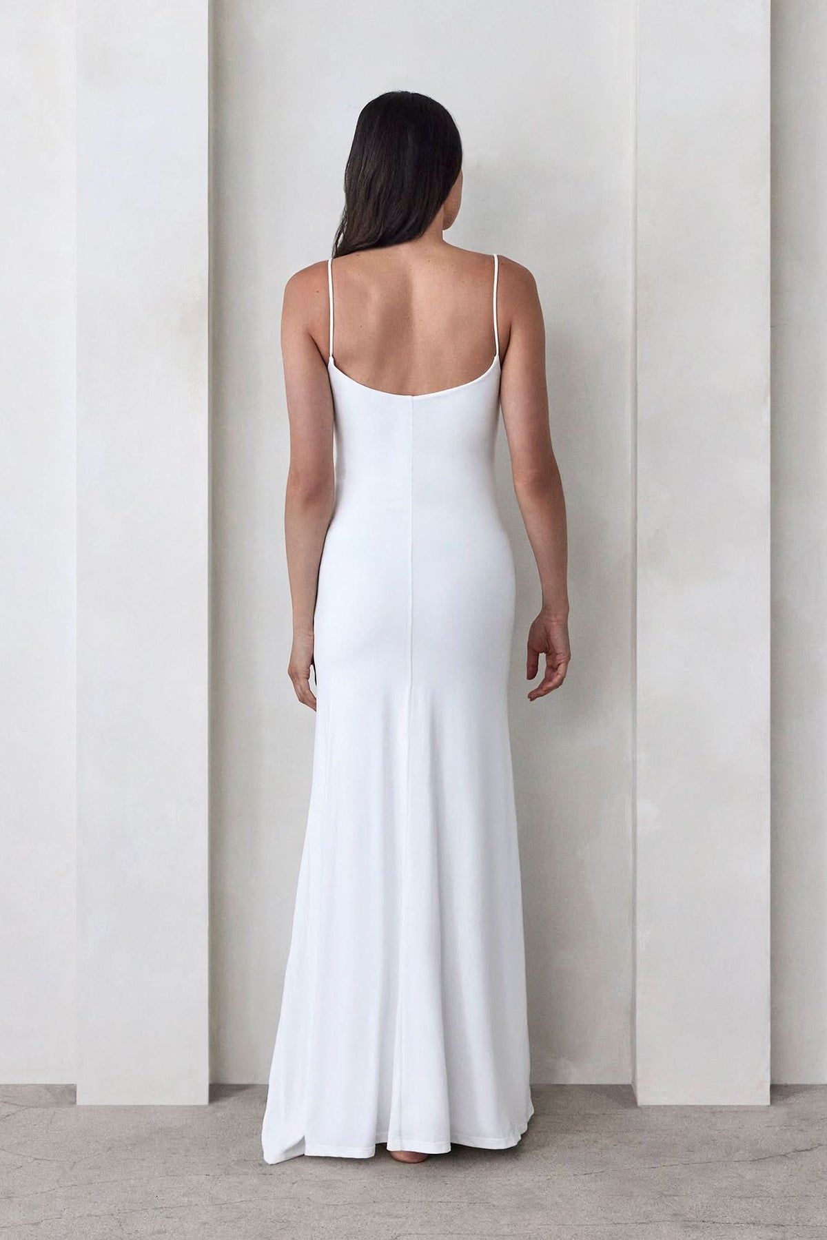 Back view of The Rosie maternity square neck maxi dress in ivory, showing spaghetti straps and maxi length against a light wall